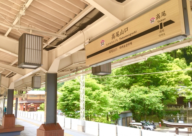 高尾山口の駅構内の写真。上部に高尾山口の駅名の書かれた看板がある。奥には木々が見える。