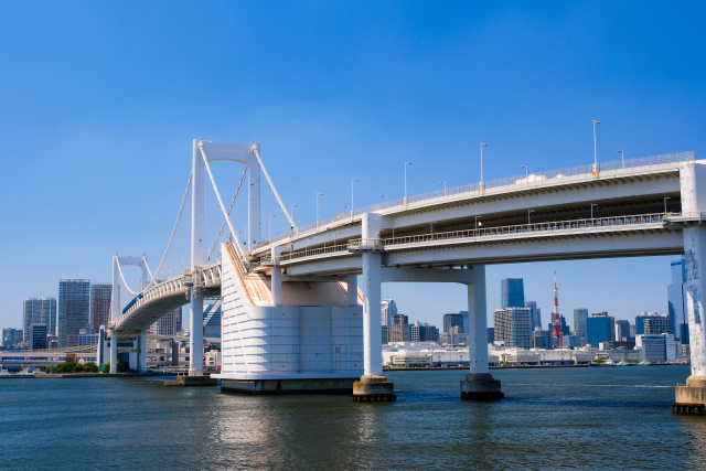 お台場側から見たレインボーブリッジの写真。橋の奥には東京タワーやその周辺のビル群が見える。