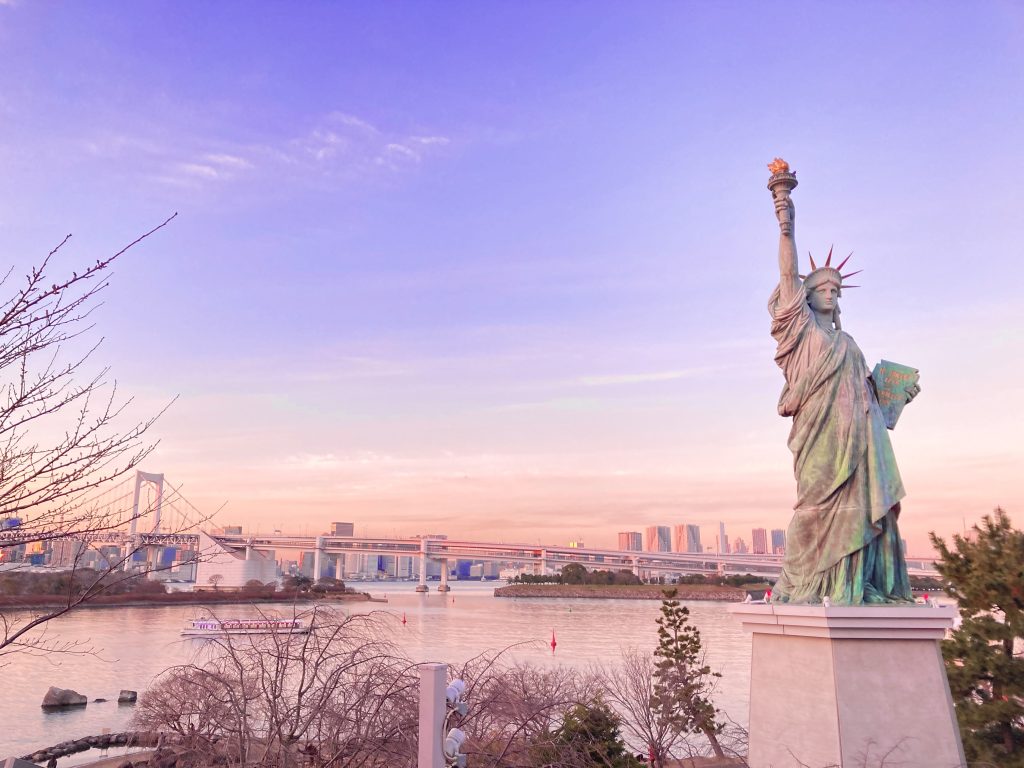 デックス東京ビーチにある自由の女神像の写真。左手前に像があり、その奥には海が広がる。レインボーブリッジも左奥側に見える。
