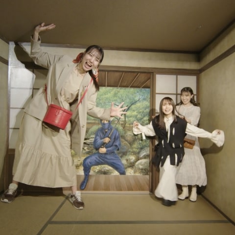 東京トリックアート迷宮館の展示室の写真。奥には忍者のイラストの書かれた壁。右には錯覚で小さくなった人。左には錯覚で大きくなった人。