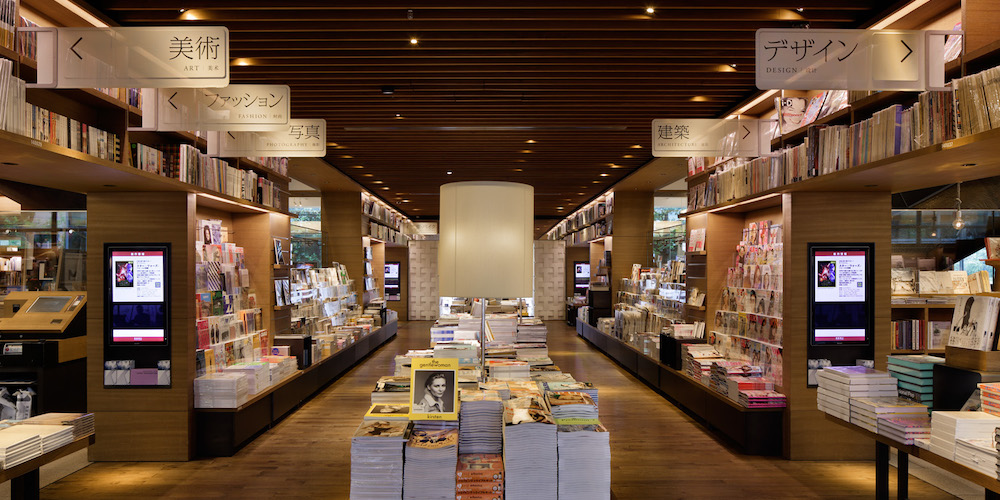 代官山 蔦屋書店の写真。中央に積まれた本。左右に本棚が手前から奥に向けて中心を向く形で連なっている。