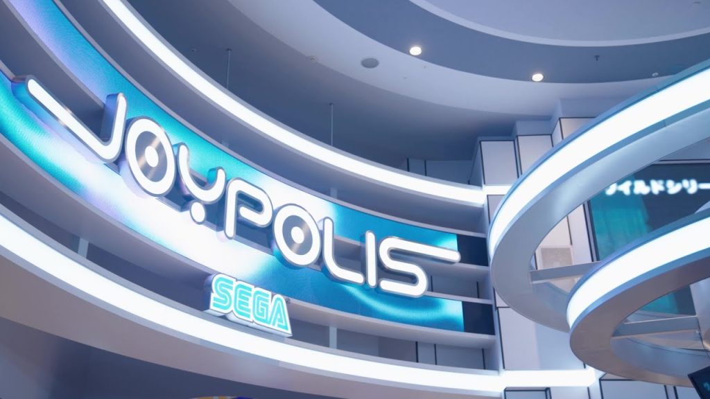 東京ジョイポリスの入口上看板の写真。JOYPOLISと書かれた下にSEGAの文字。近未来的で水色と白をメインにしたカラーリング。