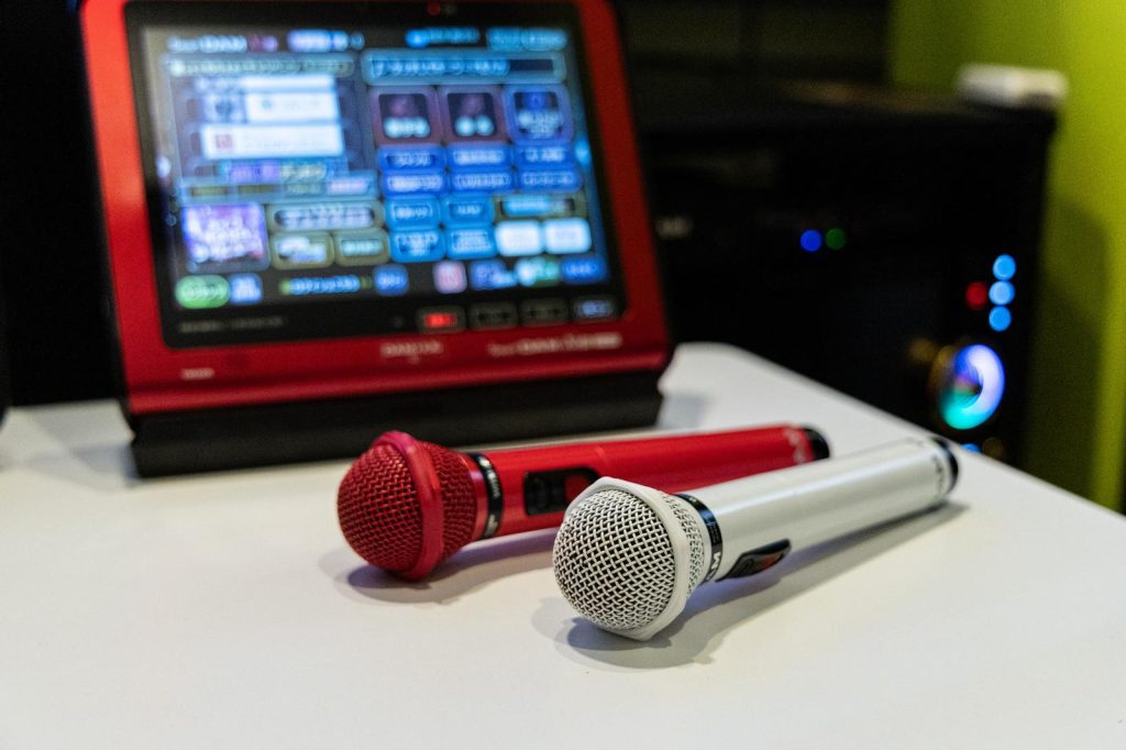 カラオケルーム内の写真。テーブルにはマイクと操作用のタブレットがある。