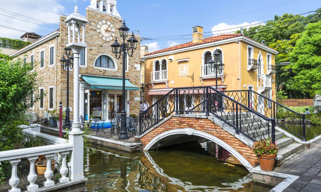 ゴシックな建物と川の写真。奥にはヨーロッパ風の建物が２つ。２階建て。その周りを川が囲んでいる。その建物にアクセスするのにヨーロッパ風の橋がかかってる。